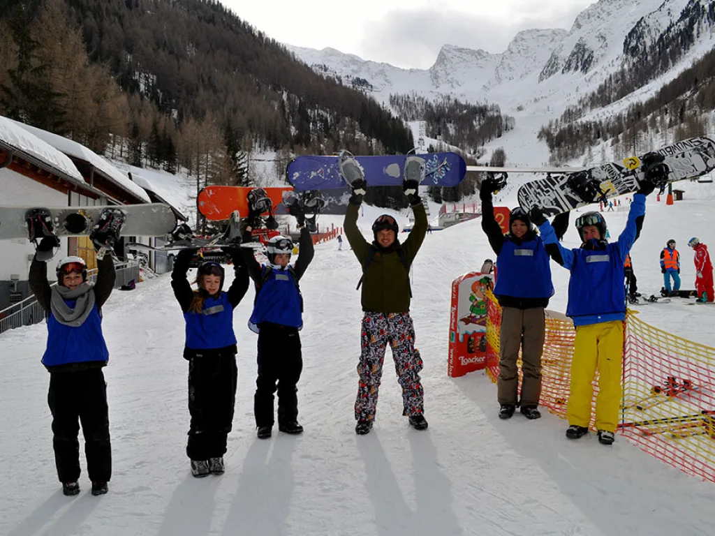 Jugendliche halten am Zielbereich ihre Snowboards hoch.